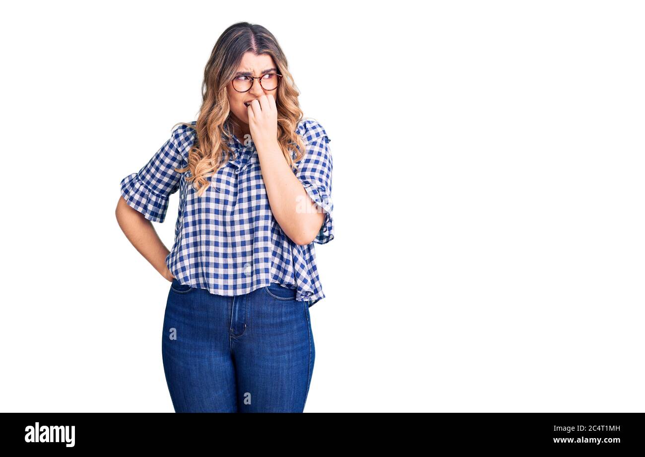 Jeune femme caucasienne portant des vêtements décontractés, aspect stressé et nerveux avec les mains sur la bouche piquant les ongles. Problème d'anxiété. Banque D'Images