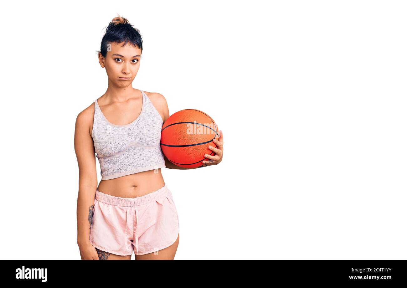 Jeune femme tenant le ballon de basket-ball attitude de pensée et d'expression sobre regardant de soi confiant Banque D'Images