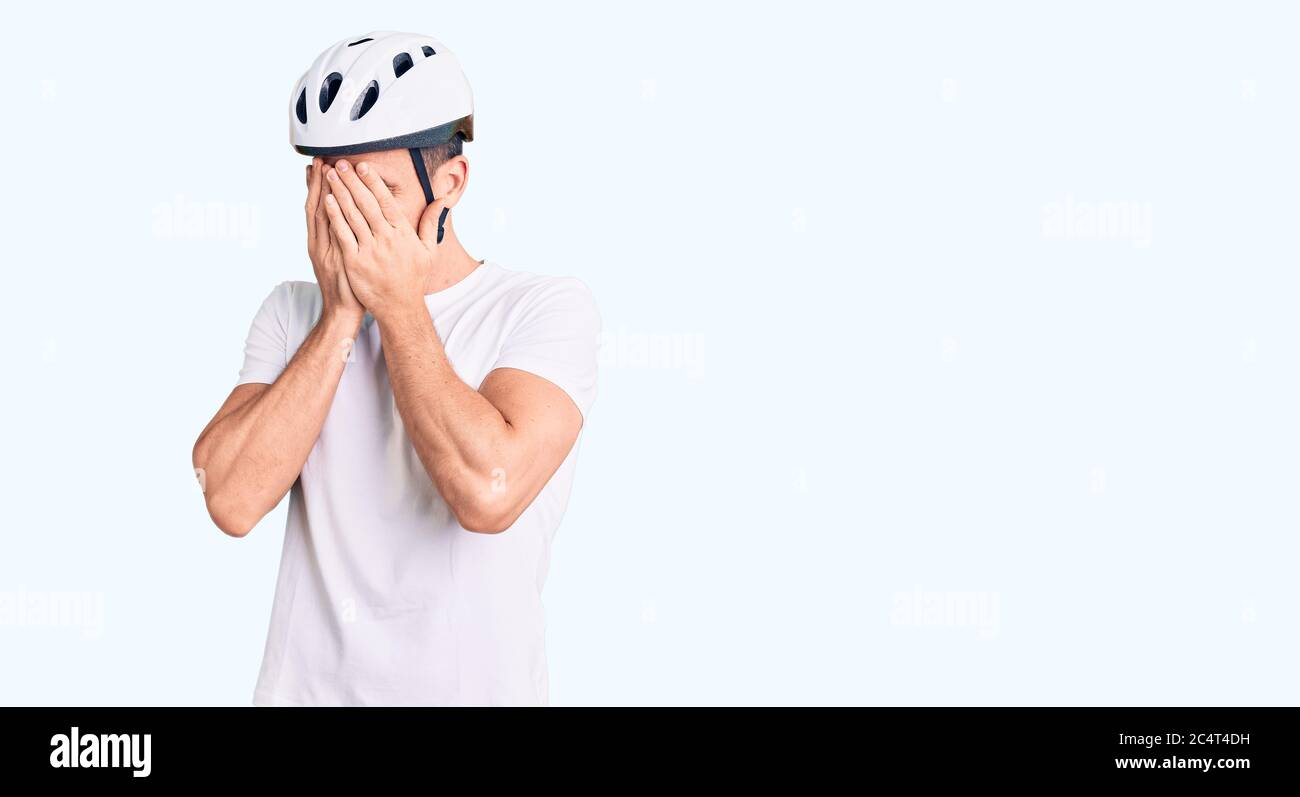 Jeune homme beau portant un casque de vélo avec une expression triste  couvrant le visage avec les mains en pleurant. Concept de dépression Photo  Stock - Alamy