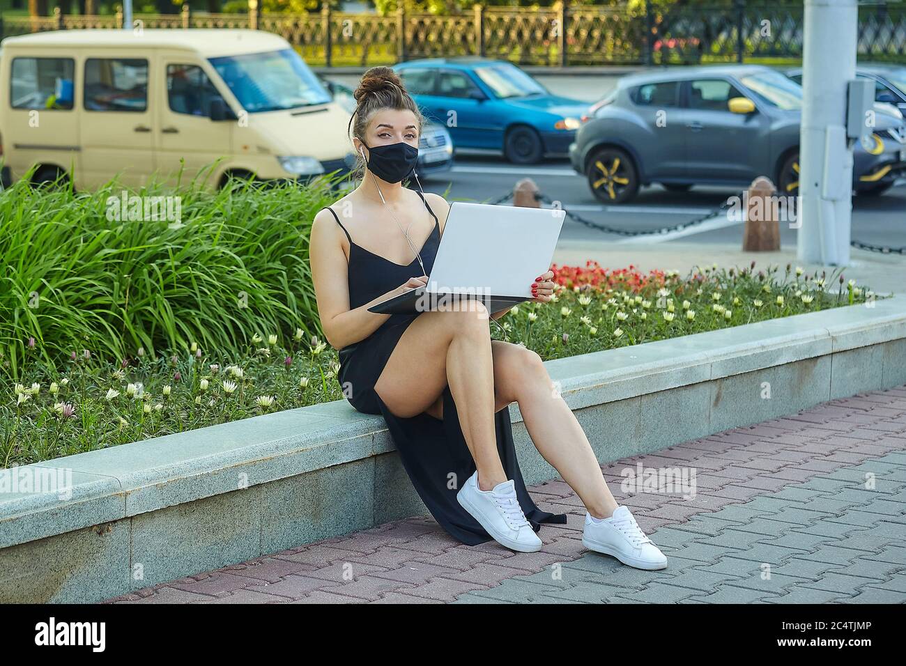 belle fille dans un masque marche dans la ville, travaillant sur un ordinateur portable. tenant un ordinateur portable et écoutant de la musique. Banque D'Images