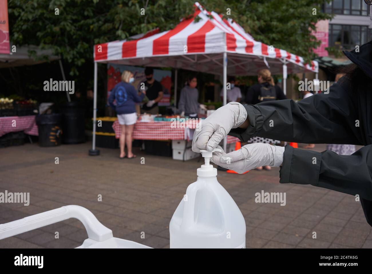 Un acheteur de gants en nitrile utilise un désinfectant pour les mains fourni aux clients du marché agricole du samedi à Lake Oswego, Oregon, le 27 juin 2020. Banque D'Images