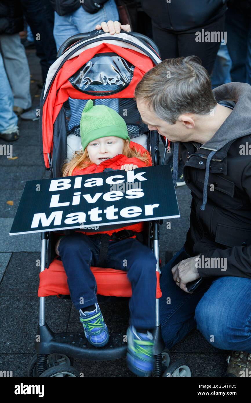 Seattle, États-Unis. 27 novembre 2015. Une petite fille dans poussette tient un signe de la matière de la vie noire accompagné de son père au rassemblement BLM. Banque D'Images