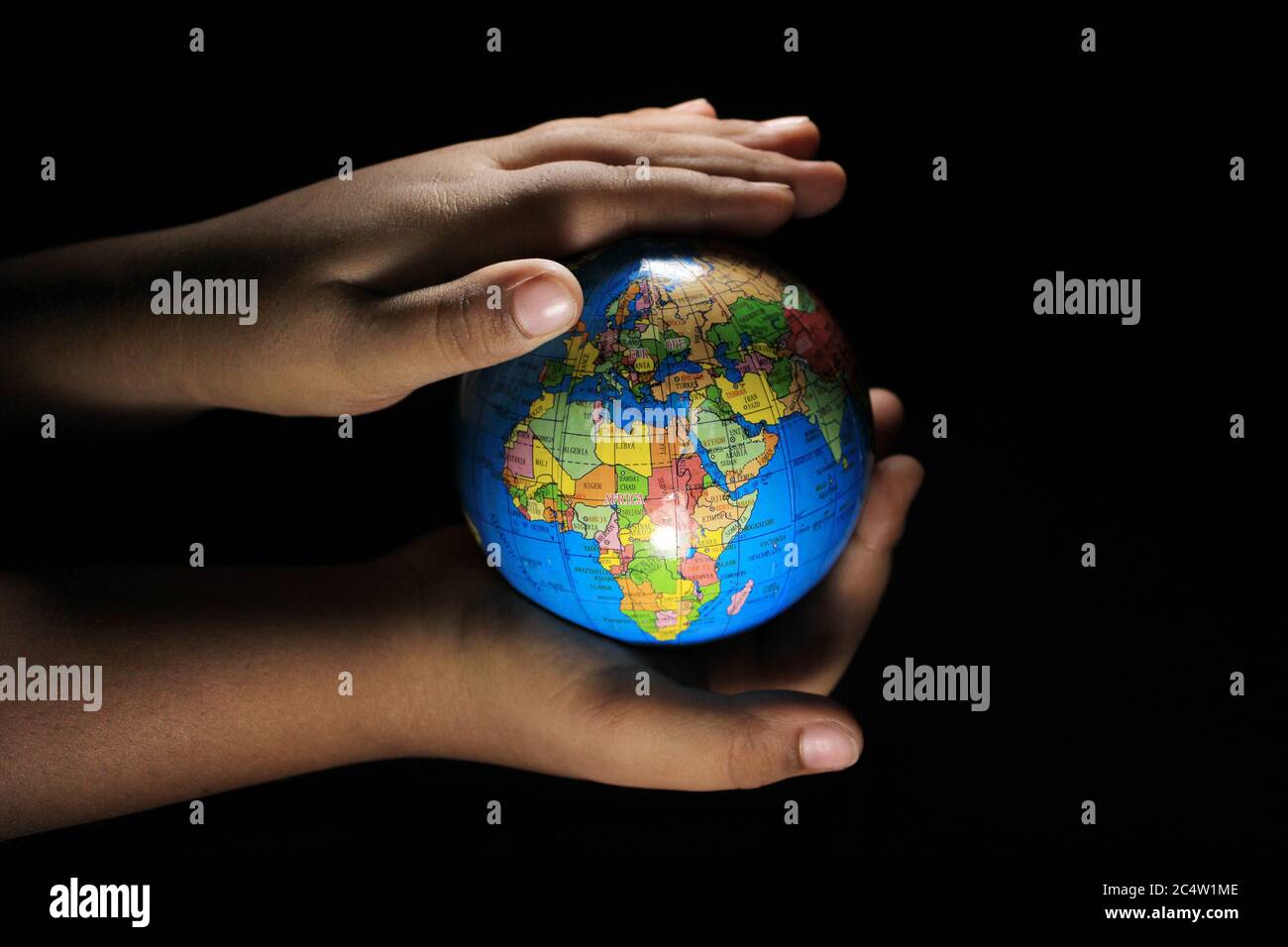Les enfants tiennent le globe terrestre sur fond noir. Globe terrestre isolé sur fond noir. Globe scolaire sur fond noir. Banque D'Images