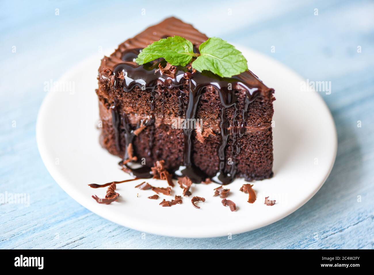 Gâteau sauce chocolat délicieux dessert servi sur la table / tranche de  gâteau sur la plaque blanche avec garniture chocolat et feuille de menthe  Photo Stock - Alamy