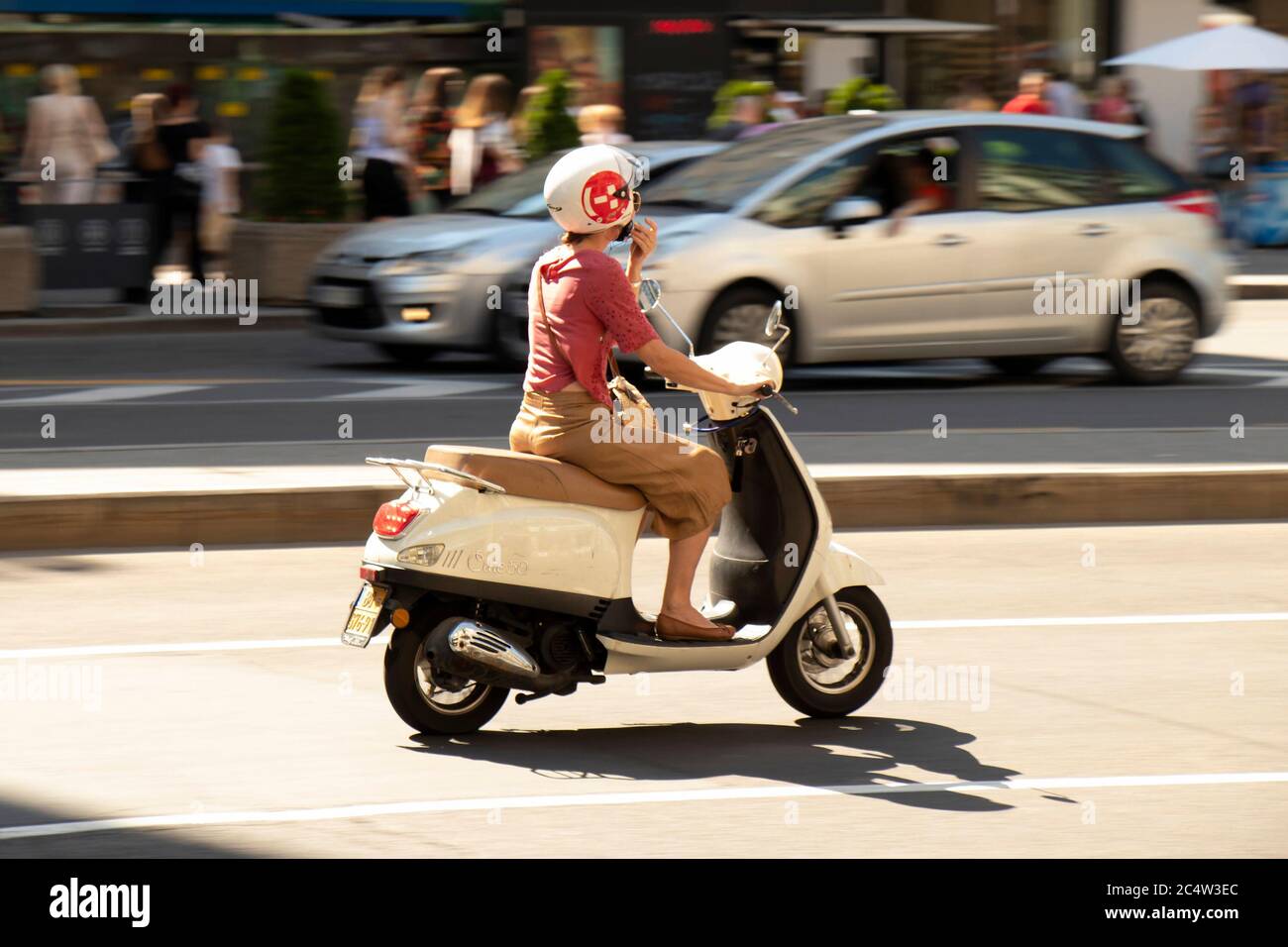 Belgrade, Serbie - 25 juin 2019 : flou de mouvement d'une femme à cheval sur un vespa dans la ville circulation de rue en été chaleur, panoramique tourné Banque D'Images