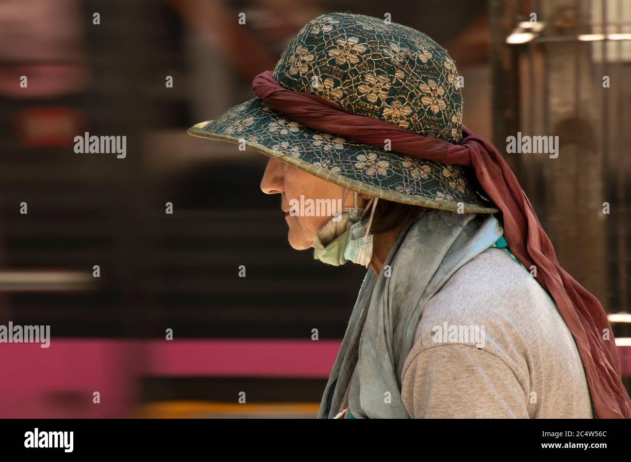 Belgrade, Serbie - 25 juin 2020 : femme âgée d'époque portant des masques chirurgicaux sales et un chapeau avec un foulard marchant dans la rue de la ville, gros plan Banque D'Images
