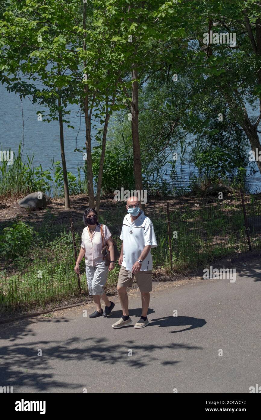 Un couple d'âge moyen portant des masques chirurgicaux va pour une promenade d'exercice autour du lac à Kissena Park, Flushing, Queens, New York City.Wears, port, Banque D'Images