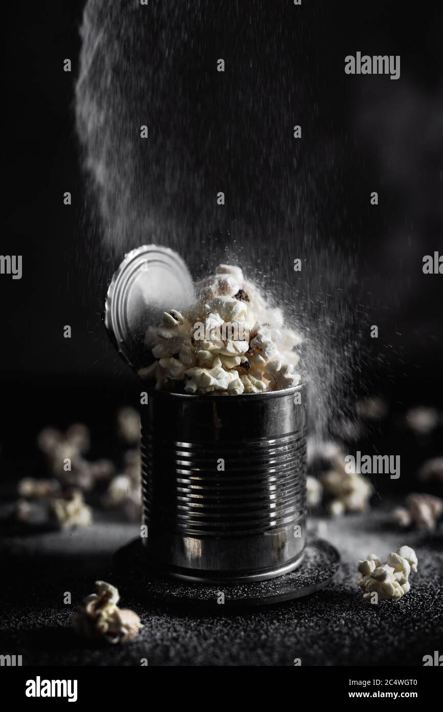Saler le pop-corn dans un moule en acier sur fond sombre, photo moody Banque D'Images