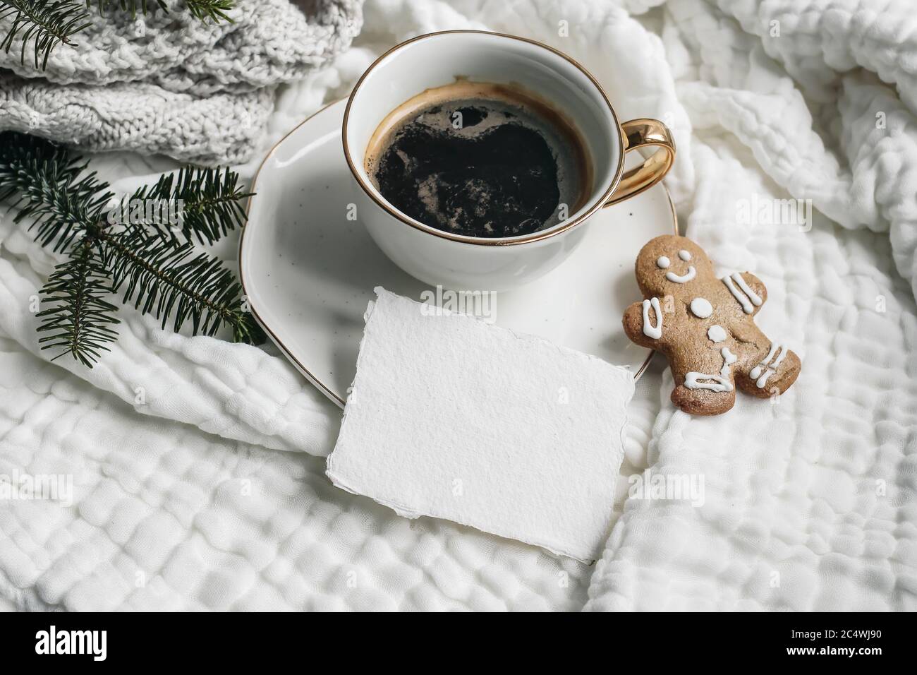 Composition de Noël. Tasse de café, maquette de carte en coton vierge, biscuit au pain d'épice et branches de sapin sur toile de table en coton mousselé blanc, jeté. Élevée Banque D'Images