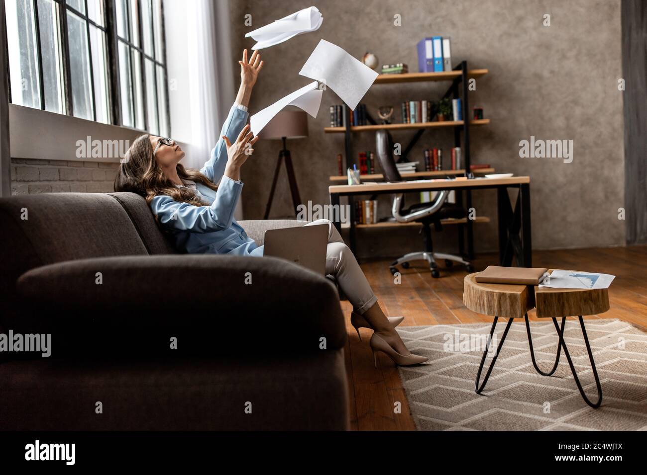 Une jeune femme d'affaires fatiguée du travail acharné avec un ordinateur portable au bureau Banque D'Images