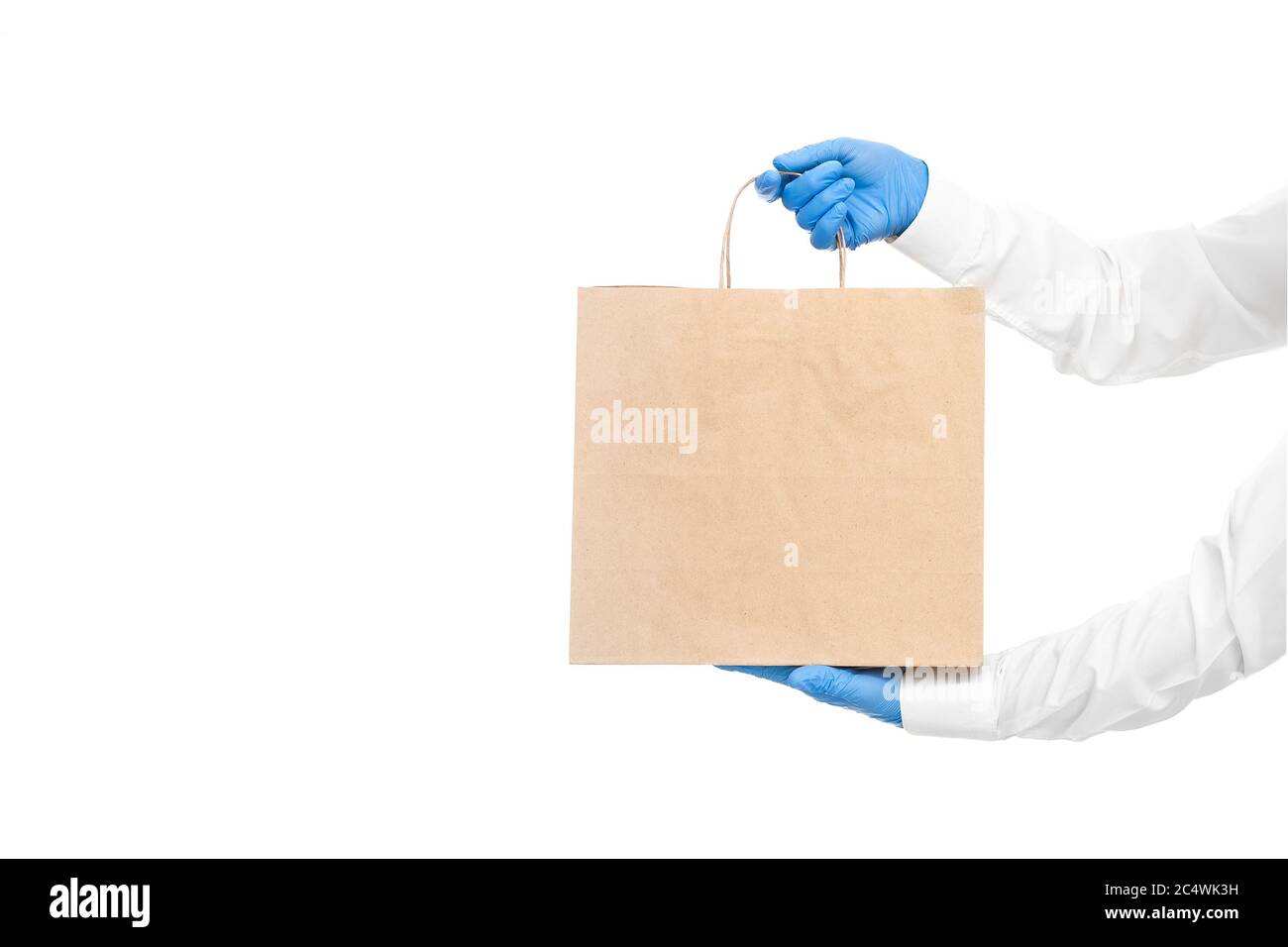 mains dans des manches blanches dans des gants stériles de messagerie pour la livraison sûre d'aliments dans un emballage écologique pendant la quarantaine du coronavirus covid-19 pa Banque D'Images