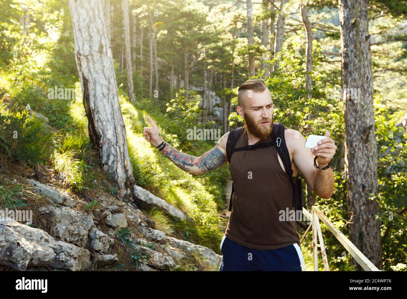 Homme de randonnée élégant barbu utilisant la navigation gps pour se positionner sur le sentier de montagne et pense où aller. Concept de technologie Banque D'Images