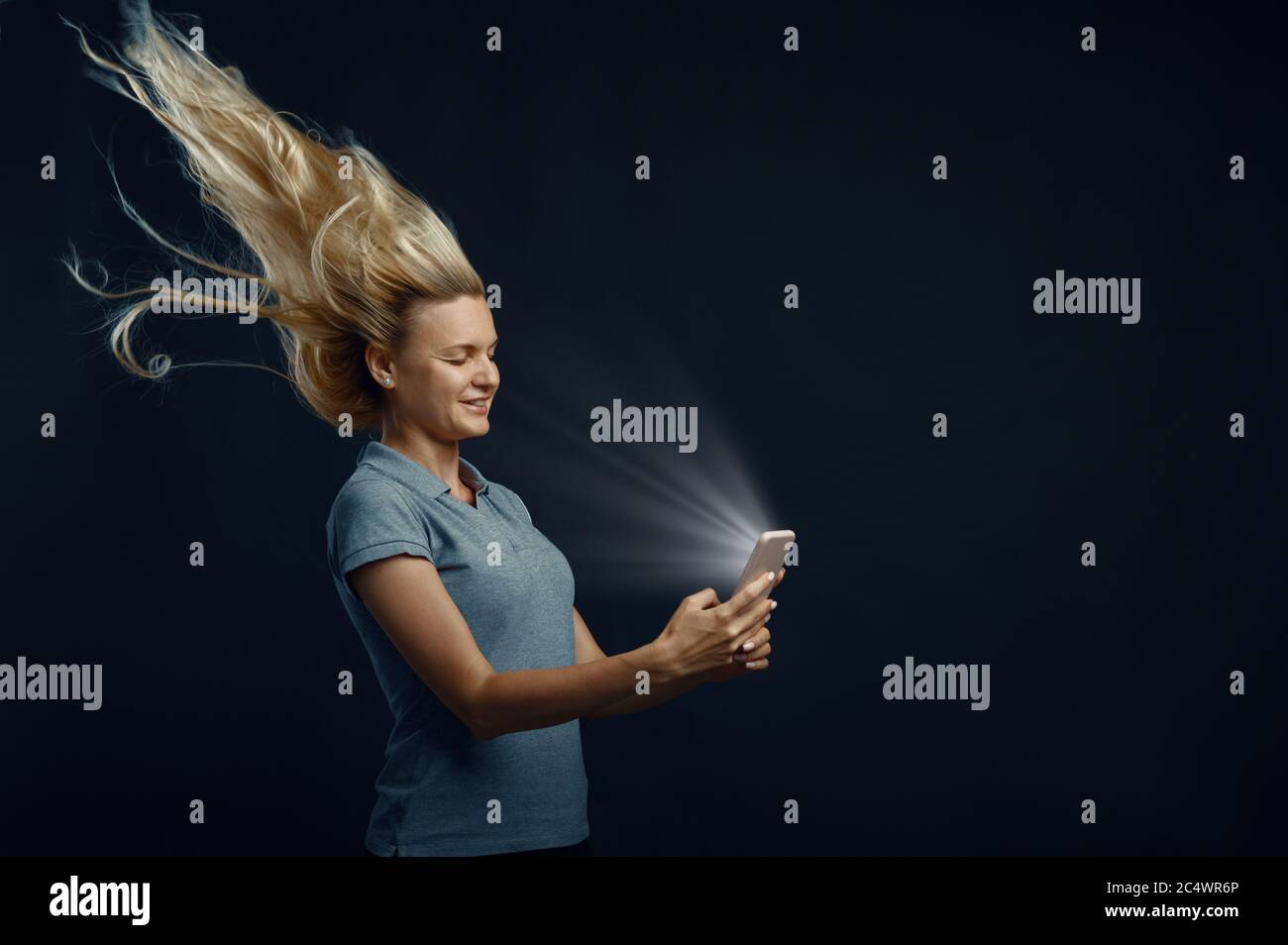 Femme regardant le téléphone contre un flux d'air puissant Banque D'Images