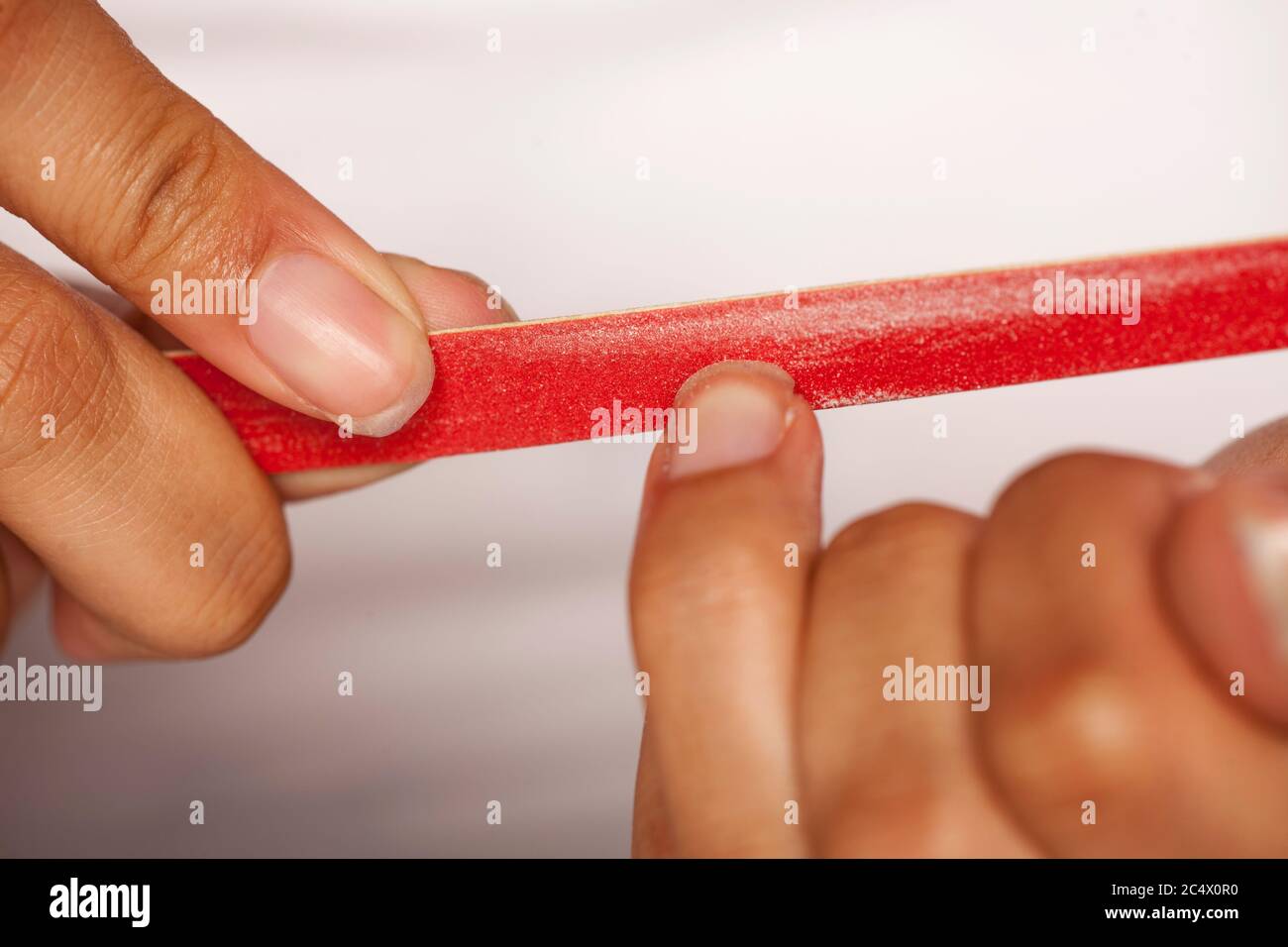 gros plan de femme à la peau foncée remplissant ses ongles de doigt sur fond blanc Banque D'Images