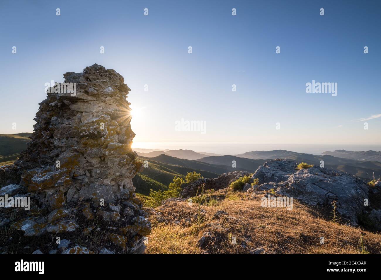 Coucher de soleil derrière un vieux mur en pierre qui donne sur la côte nord-ouest de la Corse et la mer Méditerranée Banque D'Images