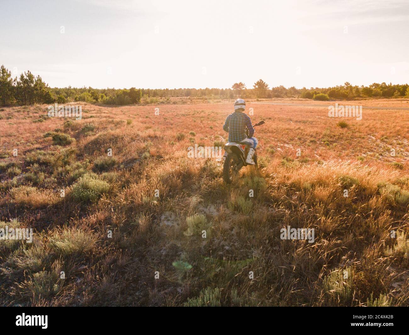 Enduro racer assis sur sa moto en regardant le coucher du soleil. Banque D'Images