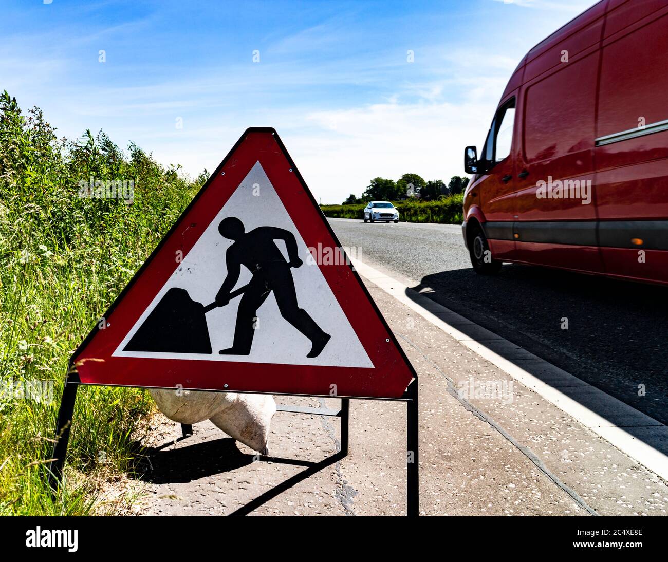 Minibus rouge passant devant un panneau d'avertissement, Écosse. Banque D'Images