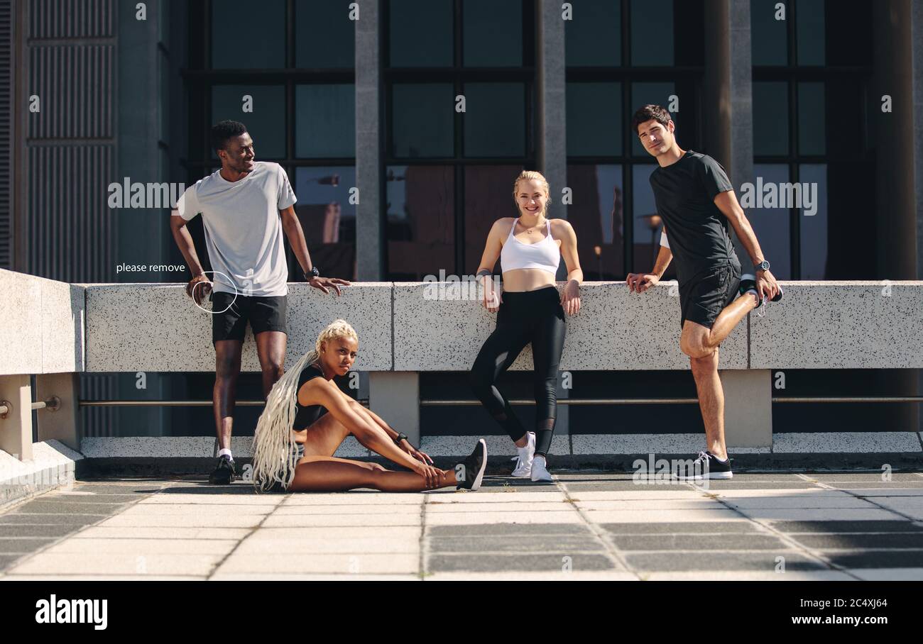 groupe de fitness se relaxant ensemble après l'entraînement. Groupe multiethnique de coureurs se reposant après une séance d'entraînement dans la ville. Banque D'Images