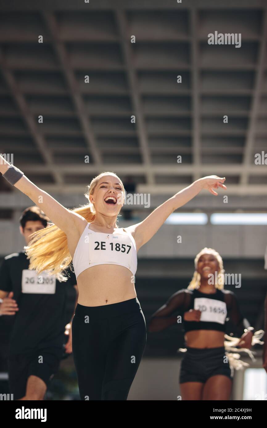 Femme à la victoire. Femme sportive qui court avec ses mains levées après avoir gagné le marathon. Banque D'Images