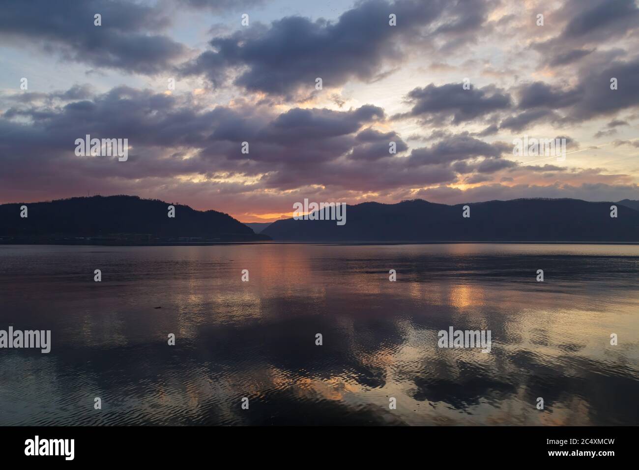 Paysages naturels étonnants, magnifique lever de soleil coloré, coucher de soleil avec des collines sur le fond et réflexion sur le Danube à Orsova, Roumanie. Banque D'Images