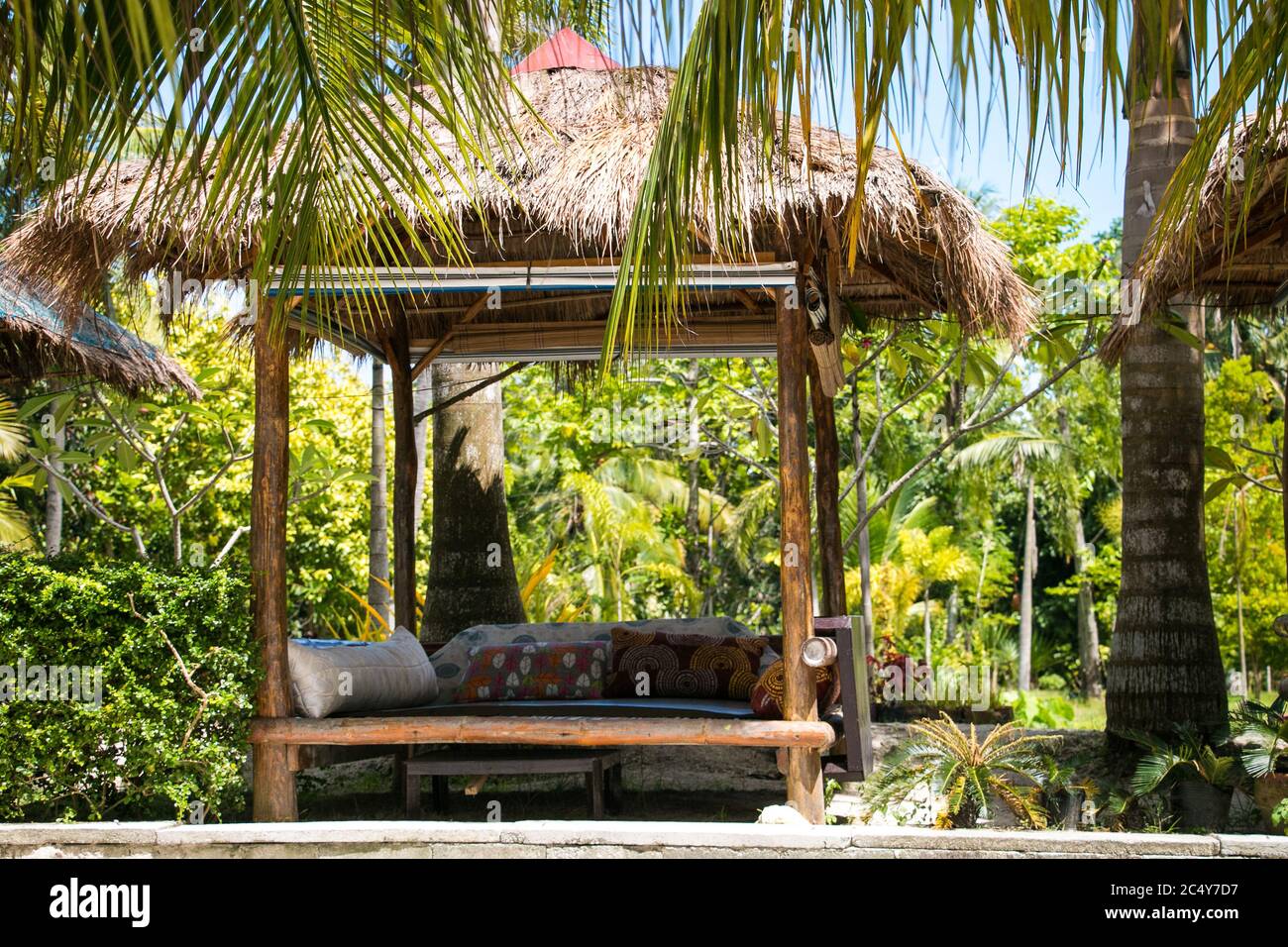 Un confortable lit de repos extérieur est installé au milieu des palmiers environnants Banque D'Images