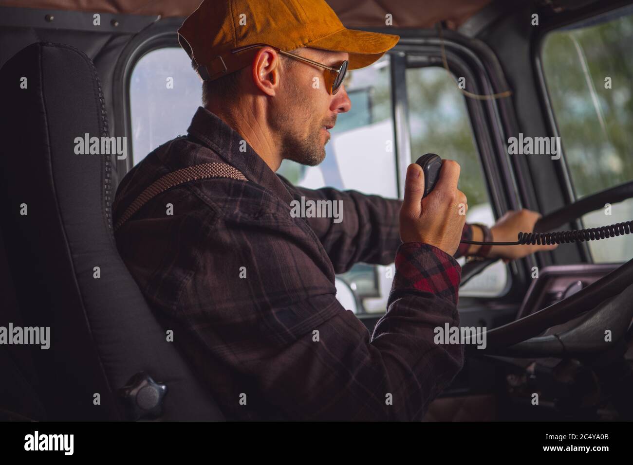 Conducteur de camion caucasien communiquant sur la radio bidirectionnelle à l'intérieur de la cabine du véhicule. Banque D'Images