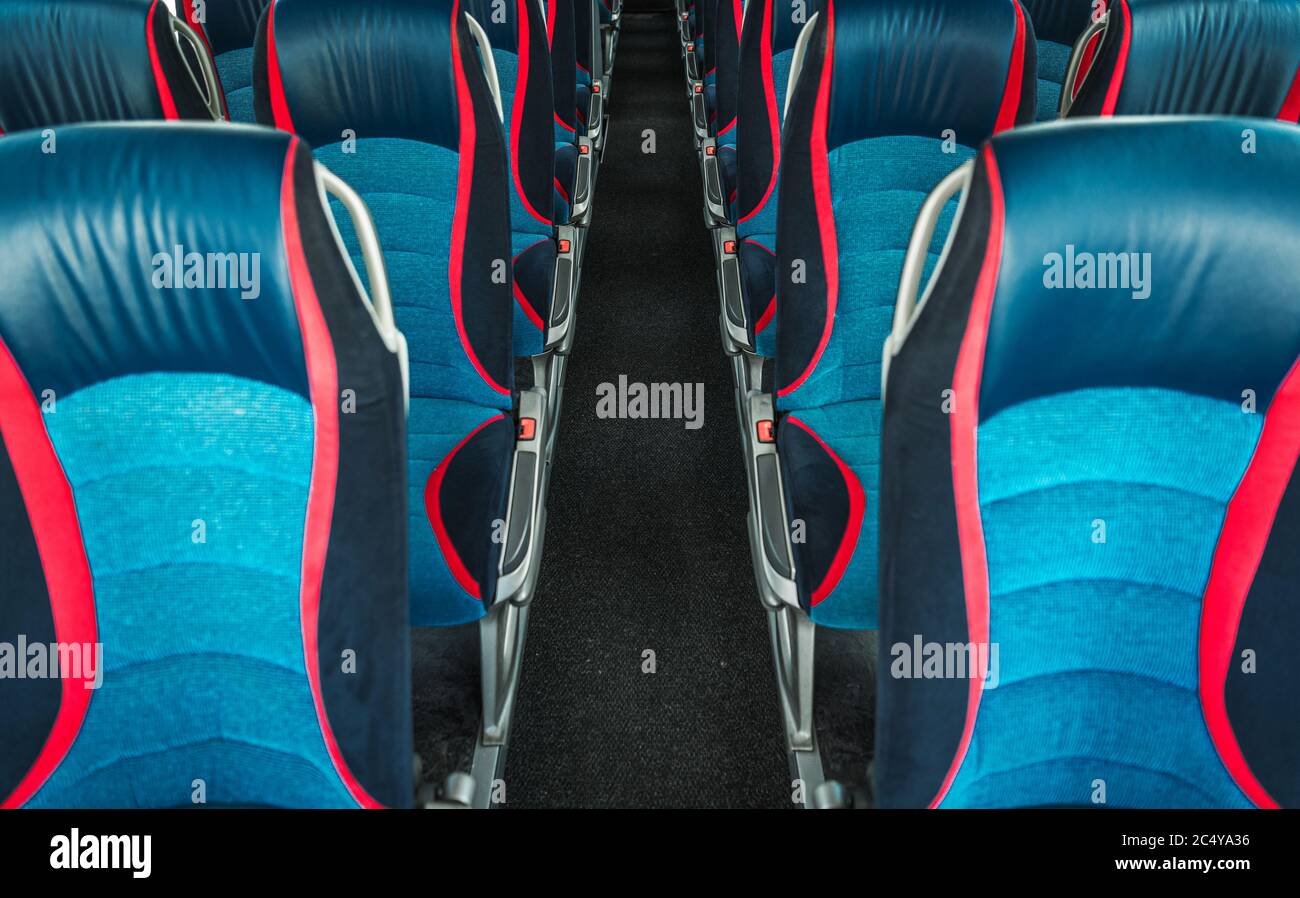 Image de l'intérieur d'un autobus de voyage vide avec rangées de sièges en tissu bleu et rouge et couloir long. Banque D'Images