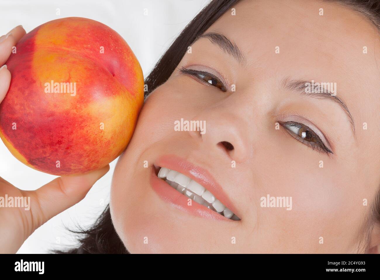 Concept Perfect Skin. Belle fille tenant un Peach près de son visage sur un fond blanc Banque D'Images