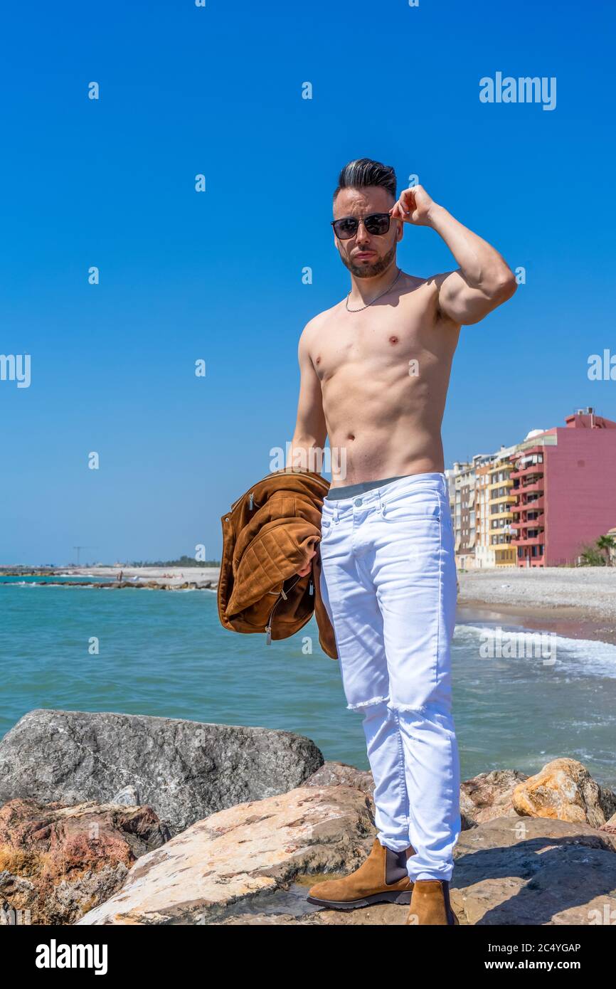 Jeune homme en pantalon blanc et style moderne posé sur la plage de la mer  Méditerranée à Burriana. Mode Photo Stock - Alamy