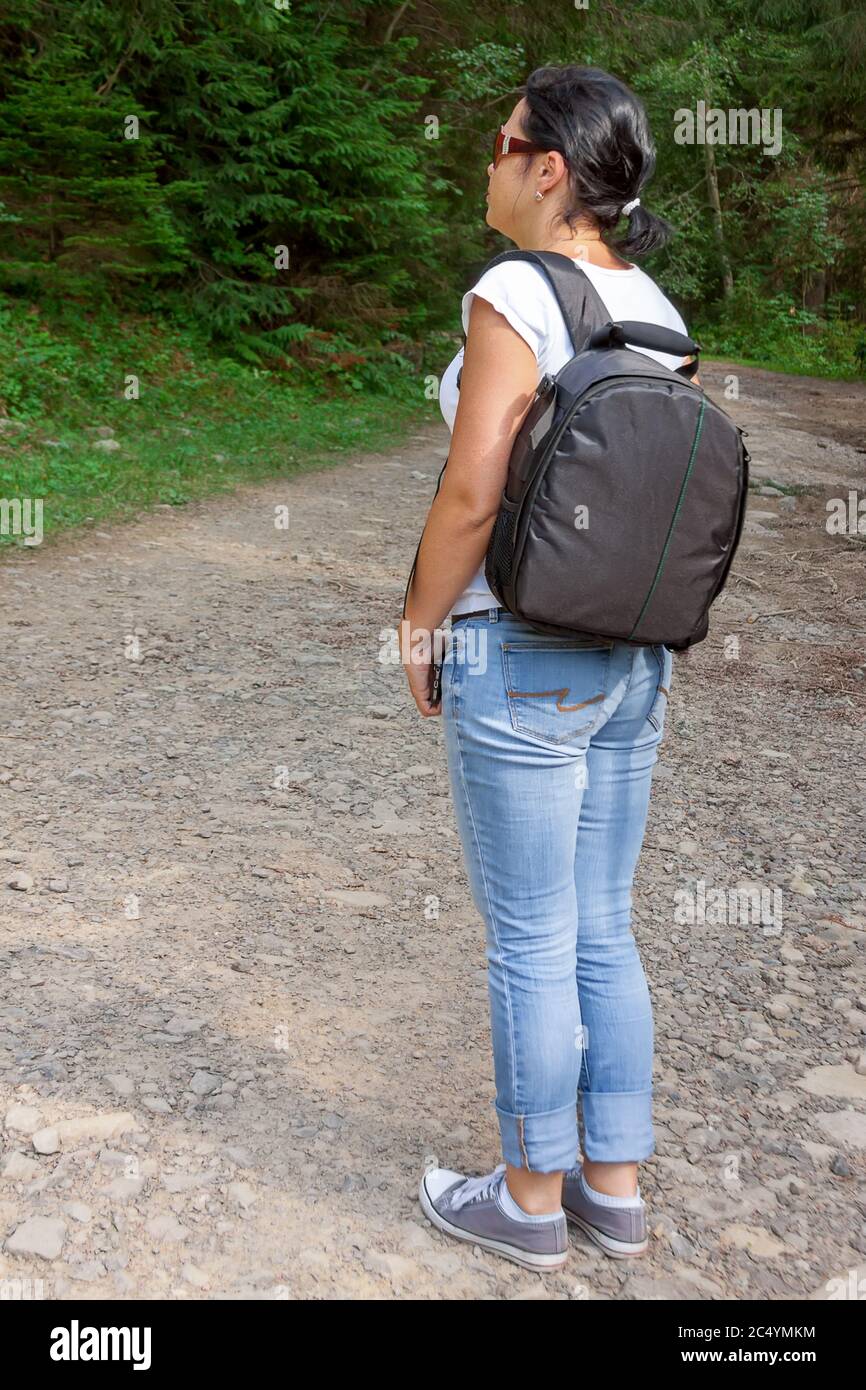 Vue arrière photo d'une jeune femme avec sac à dos debout devant Forest. Un concept de promenades touristiques dans la nature Banque D'Images