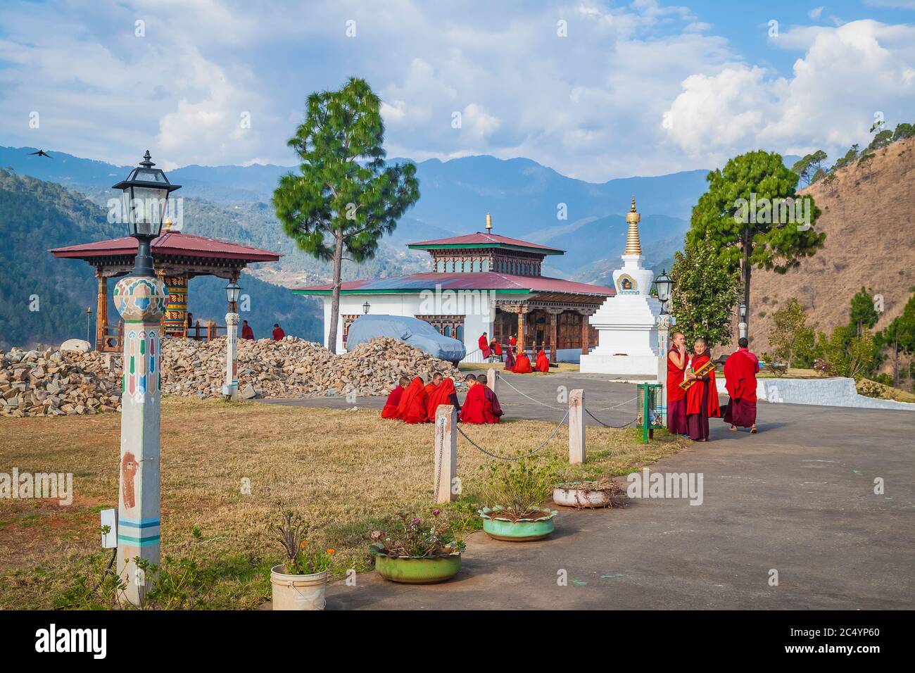 Jeunes femmes moines du monastère bouddhiste dans leurs robes rouges traditionnelles avant les classes à côté de la roue de prière sur le fond du Himal Banque D'Images