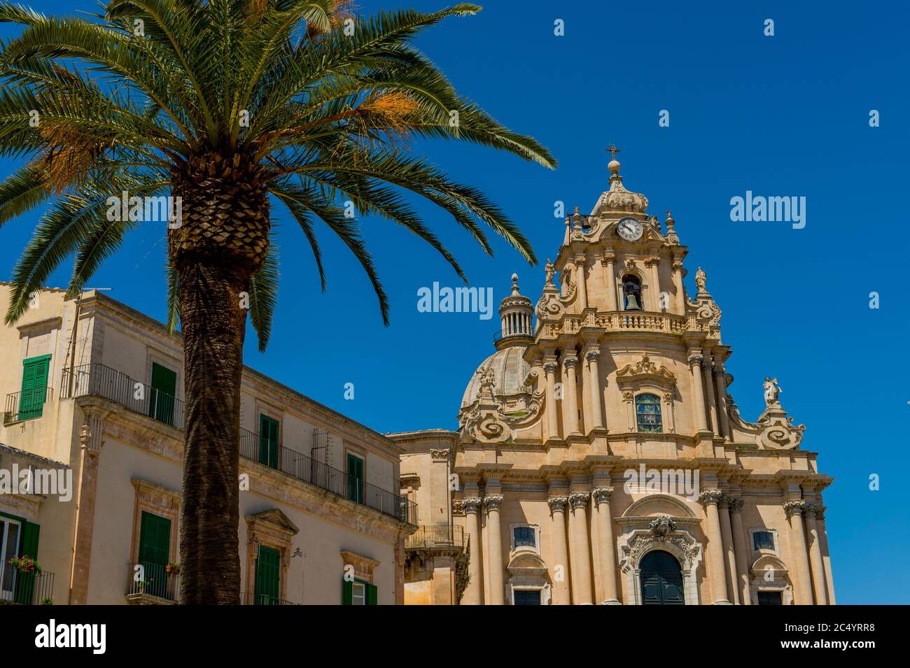 Un palmier en face de la cathédrale de San Giorgio (Saint George) dans la ville de Ragusa Ibla, sur l'île de Sicile en Italie. Banque D'Images