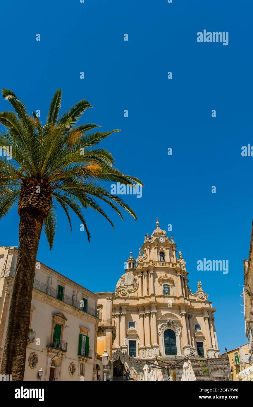 Un palmier en face de la cathédrale de San Giorgio (Saint George) dans la ville de Ragusa Ibla, sur l'île de Sicile en Italie. Banque D'Images