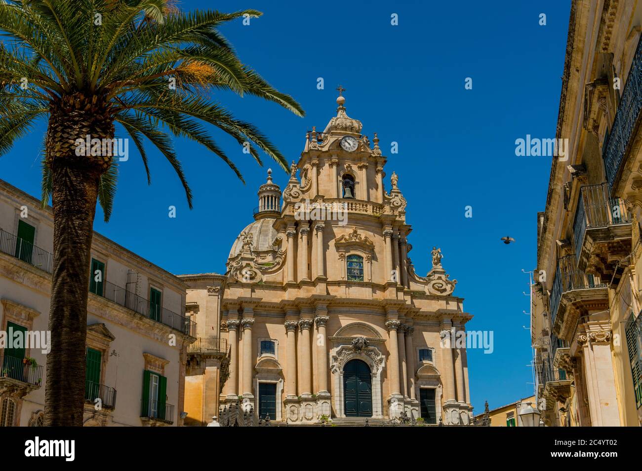 Un palmier en face de la cathédrale de San Giorgio (Saint George) dans la ville de Ragusa Ibla, sur l'île de Sicile en Italie. Banque D'Images