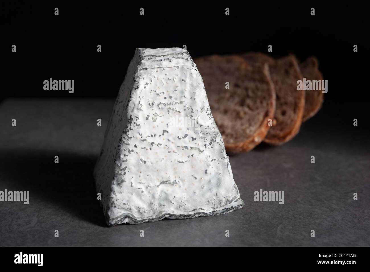 Une pyramide de fromage de chèvre recouverte de cendres avec des tranches de pain semées au levain Banque D'Images