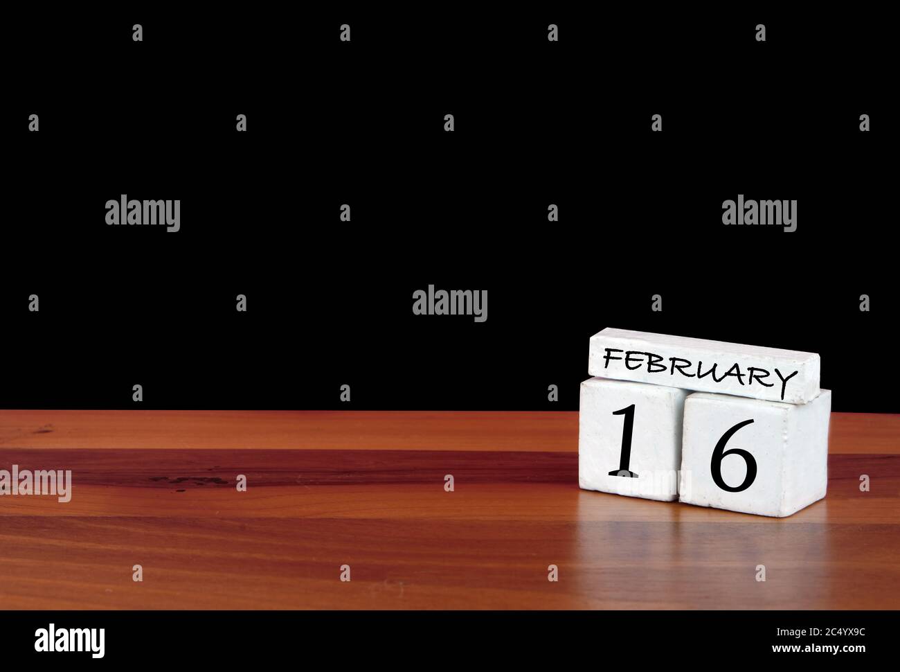 16 février. 16 jours du mois. Calendrier réfléchi sur parquet avec fond noir Banque D'Images