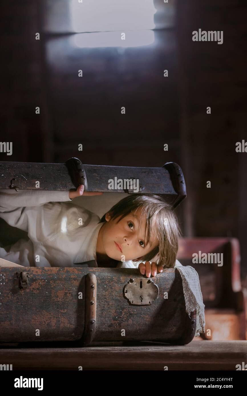 Petit enfant, garçon, se cachant dans une vieille valise vintage dans le  grenier, peur de ne pas être trouvé Photo Stock - Alamy