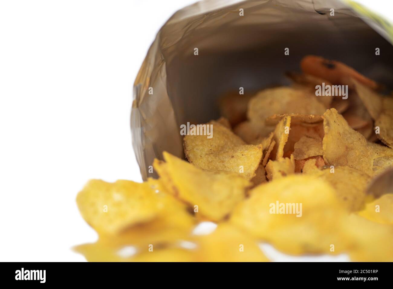 Les chips de pomme de terre versées à partir d'un sac reposent sur un fond blanc. Macro Banque D'Images