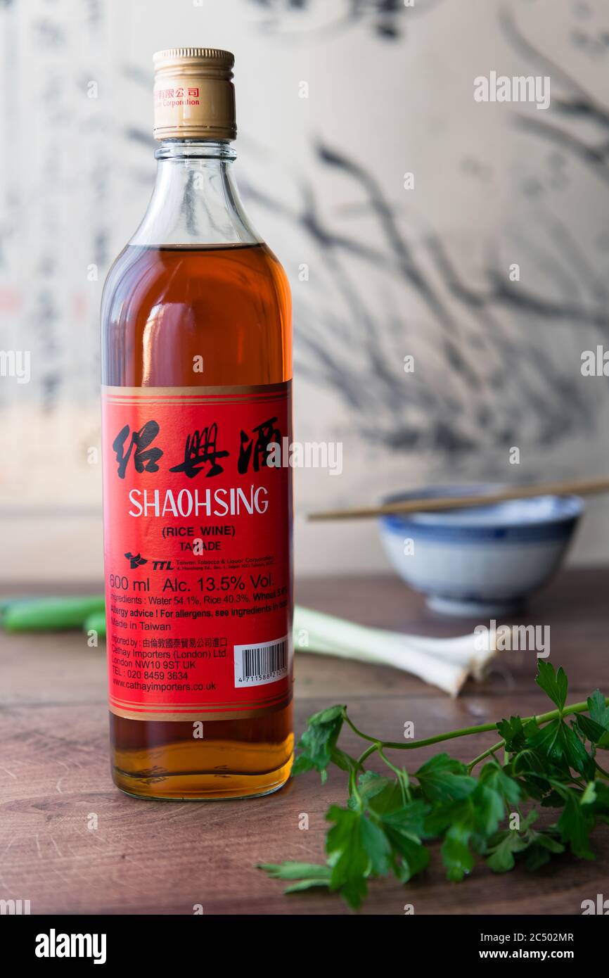 Une bouteille de vin de cuisine Shaohsing sur le dessus de la cuisine avec du persil et des oignons de printemps. Banque D'Images