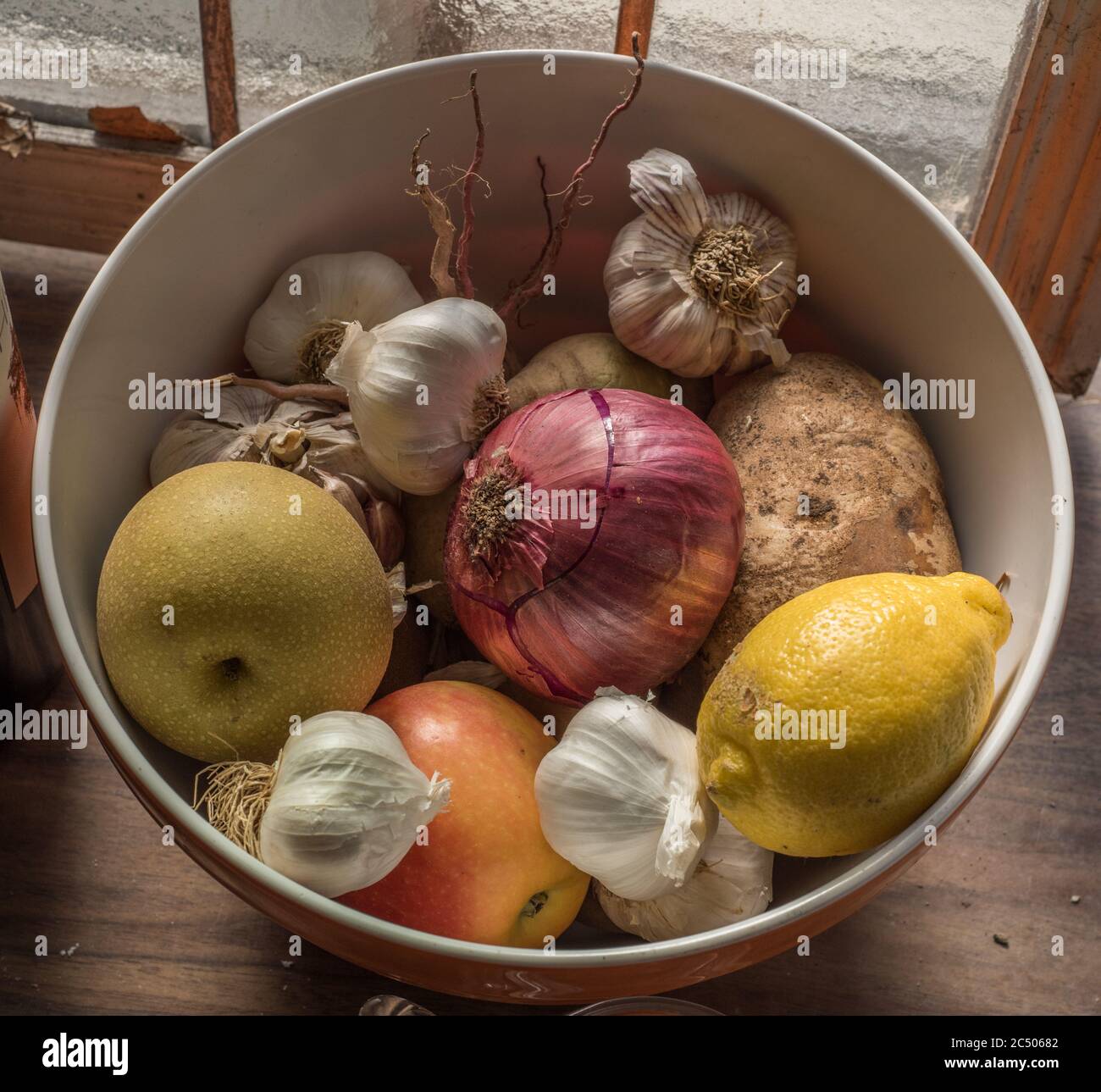 Une vie encore d'un bol de fruits et légumes mélangés assis sur un comptoir dans une cuisine. Banque D'Images