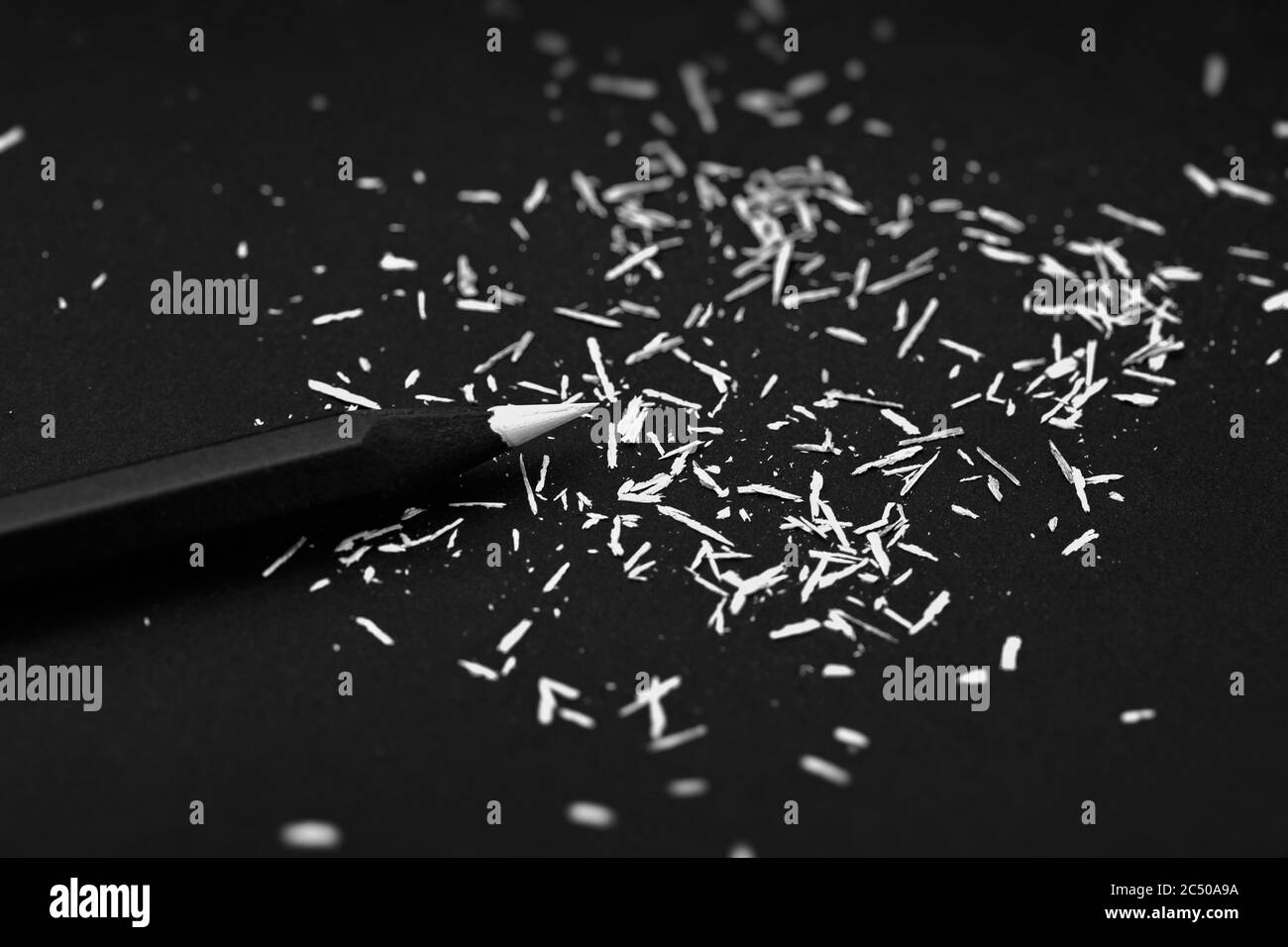 Crayon blanc sur fond noir, et copeaux des crayons. Banque D'Images