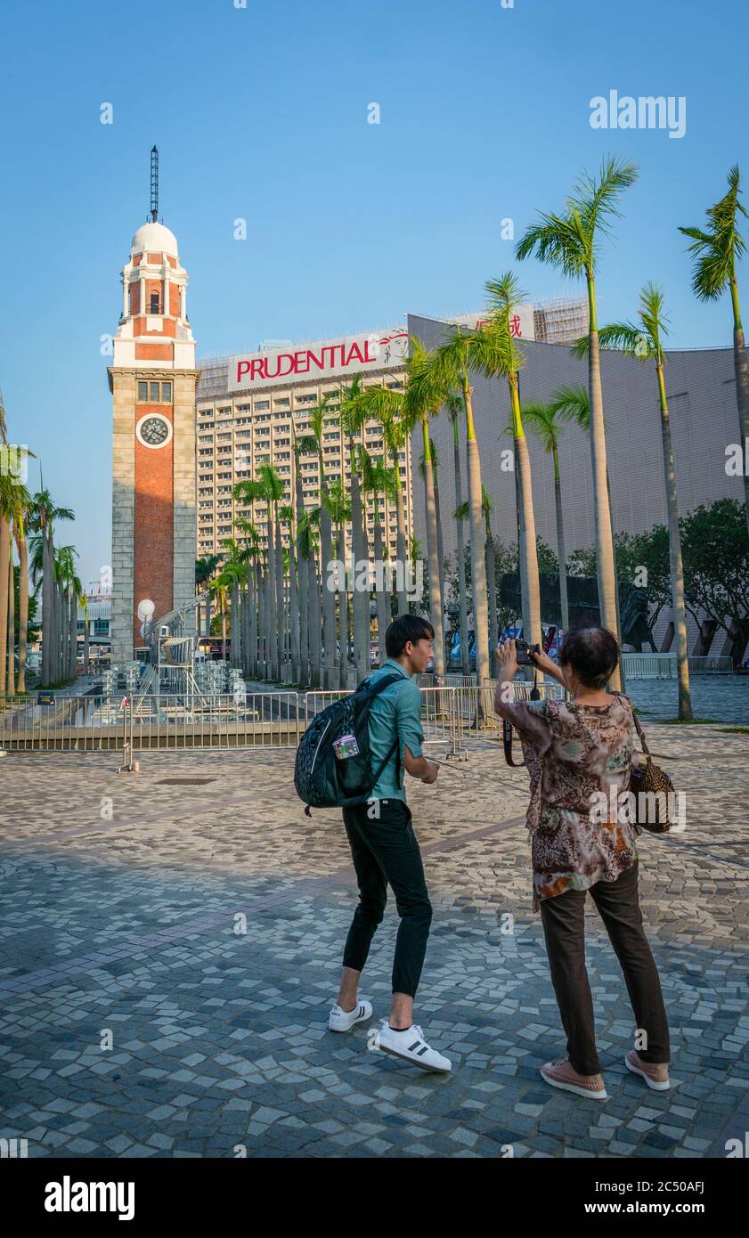 Un touriste mâle et femelle prenant des photos de la Tour de l'horloge ferroviaire du canton de Kowloon à Kowloon Tsim Sha Tsui, Hong Kong. Banque D'Images
