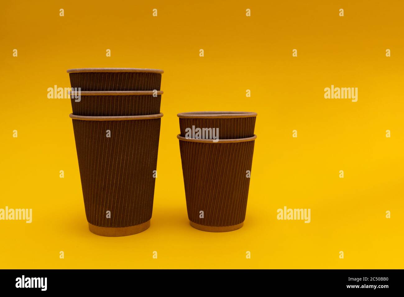 Deux récipients en papier sans couvercle se tiennent l'un dans l'autre sur le papier de fond jaune Banque D'Images