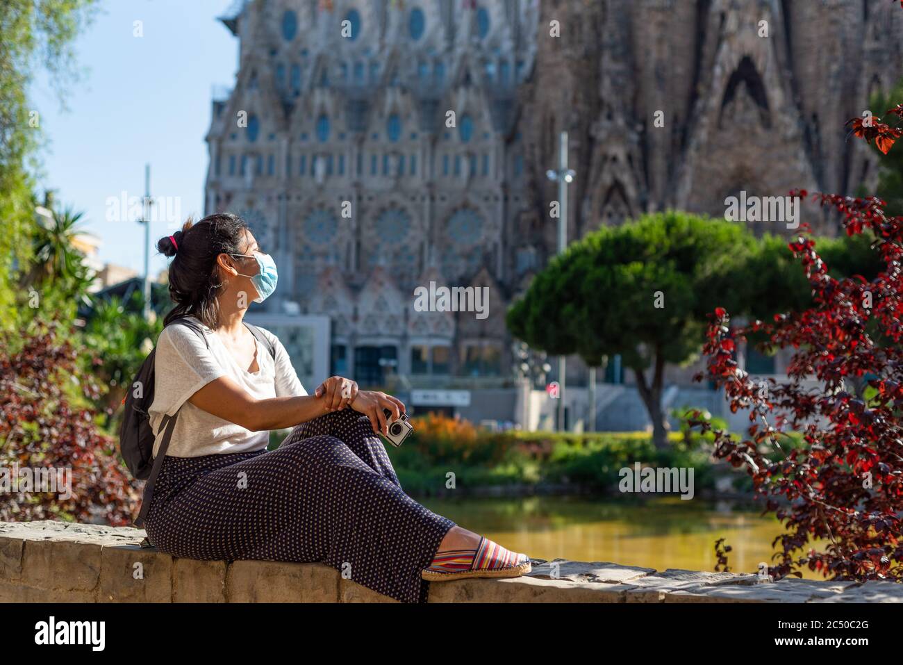 jeune et jolie femme touristique avec masque facial posant devant la sagrada familia à barcelone, symbole du tourisme à l'espagne pendant la maladie covid et Banque D'Images