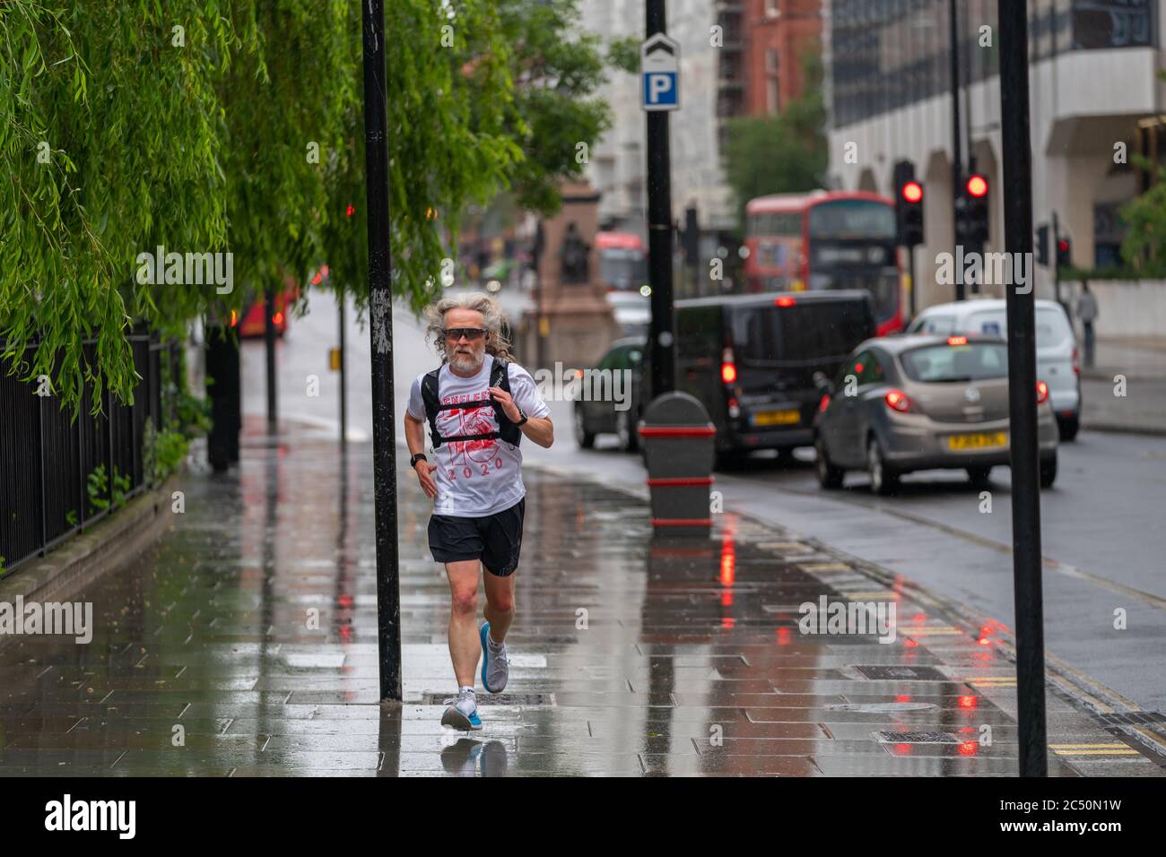 LONDRES, ANGLETERRE - 10 JUIN 2020 : un homme âgé pris dans la pluie jogging lors d'une journée de drizzly portant un t-shirt à Holborn, Londres pendant la COVID-19 Banque D'Images