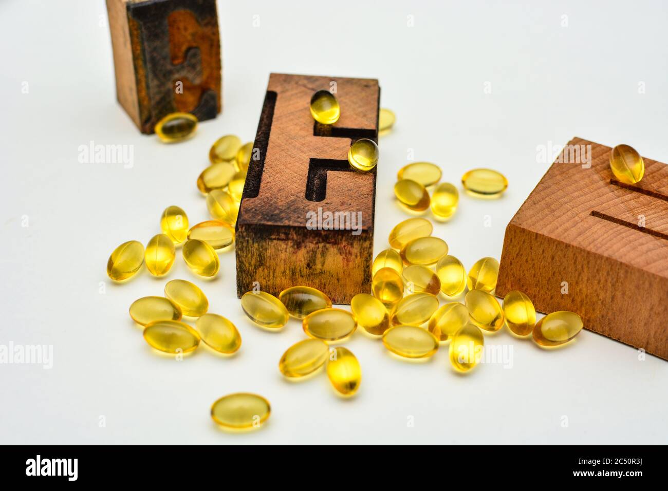 Capsules de gel souple de vitamine E et lettres typographiques en bois E. concept de soutien de la santé et de l'immunité. Banque D'Images