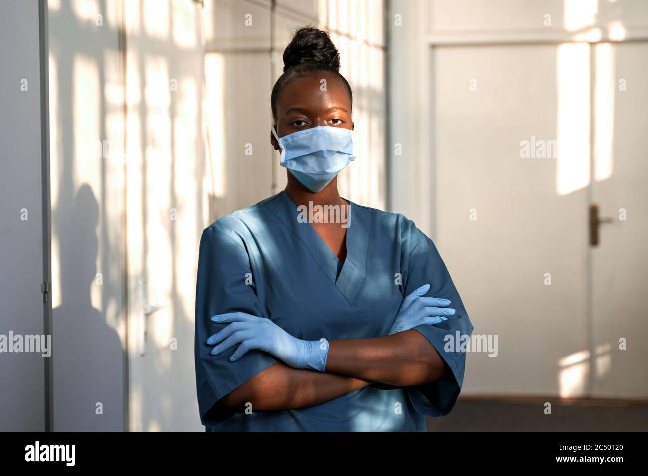Une infirmière africaine confiante porte un uniforme bleu, un masque, debout à l'hôpital. Banque D'Images