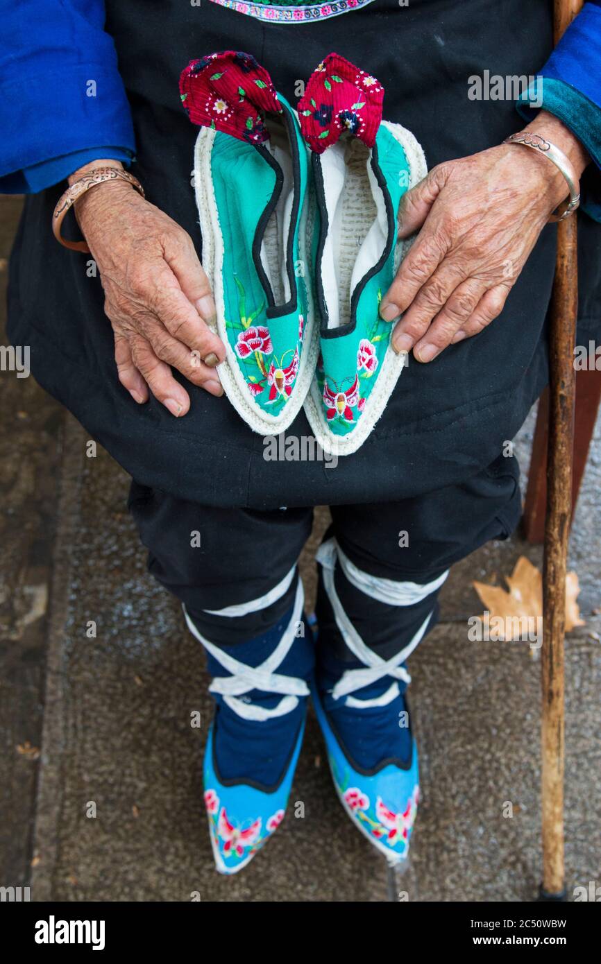 Gros plan sur une femme chinoise tenant ses petites chaussures. Elle avait  ses pieds liés (repose-pieds) également appelés pieds de Lotus Photo Stock  - Alamy