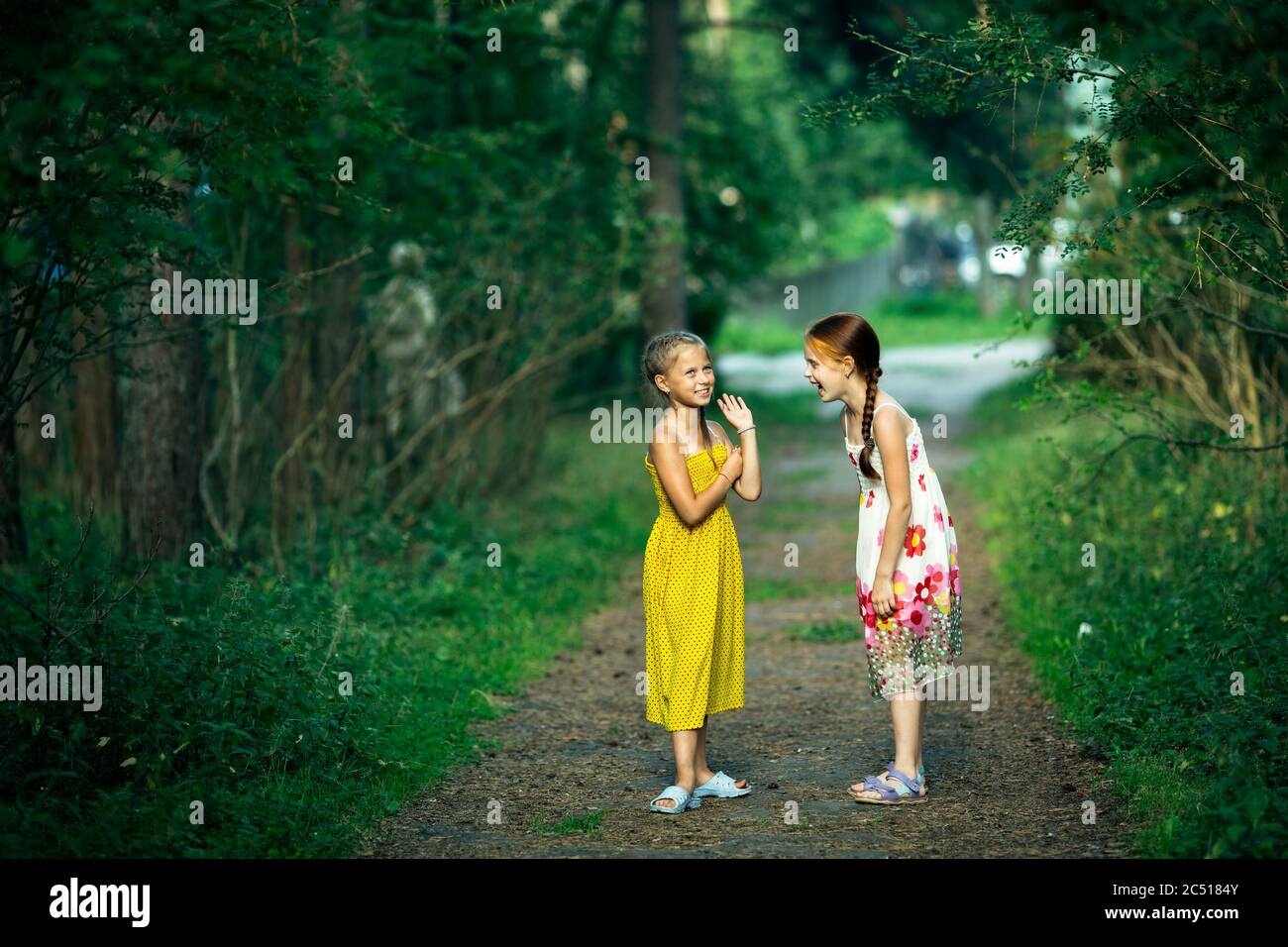 Deux petites filles amis ragots dans un parc de pins. Banque D'Images