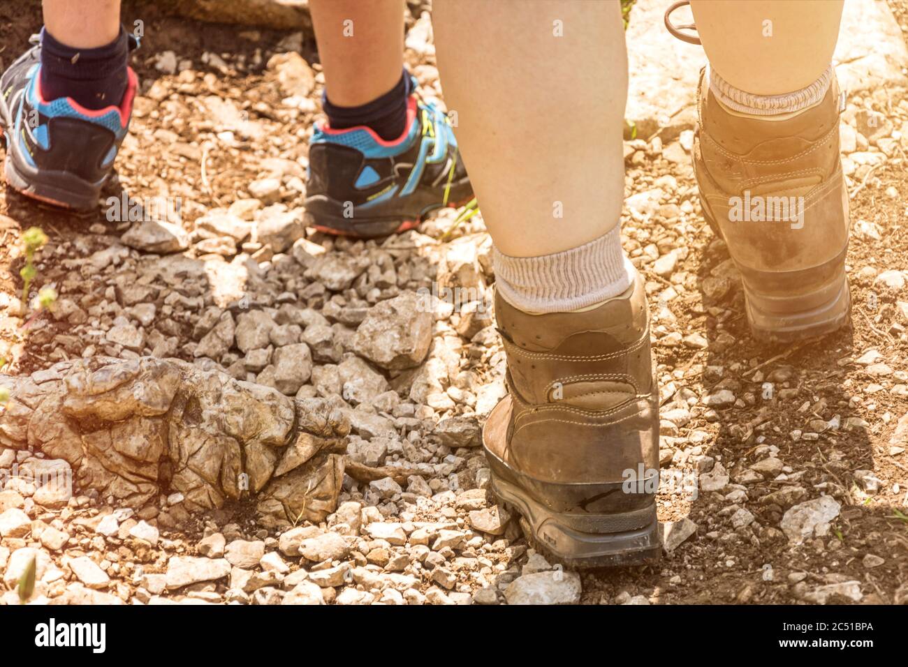 Gros plan des pieds dans des bottes de randonnée sur un sentier dans la lumière pittoresque de l'après-midi Banque D'Images